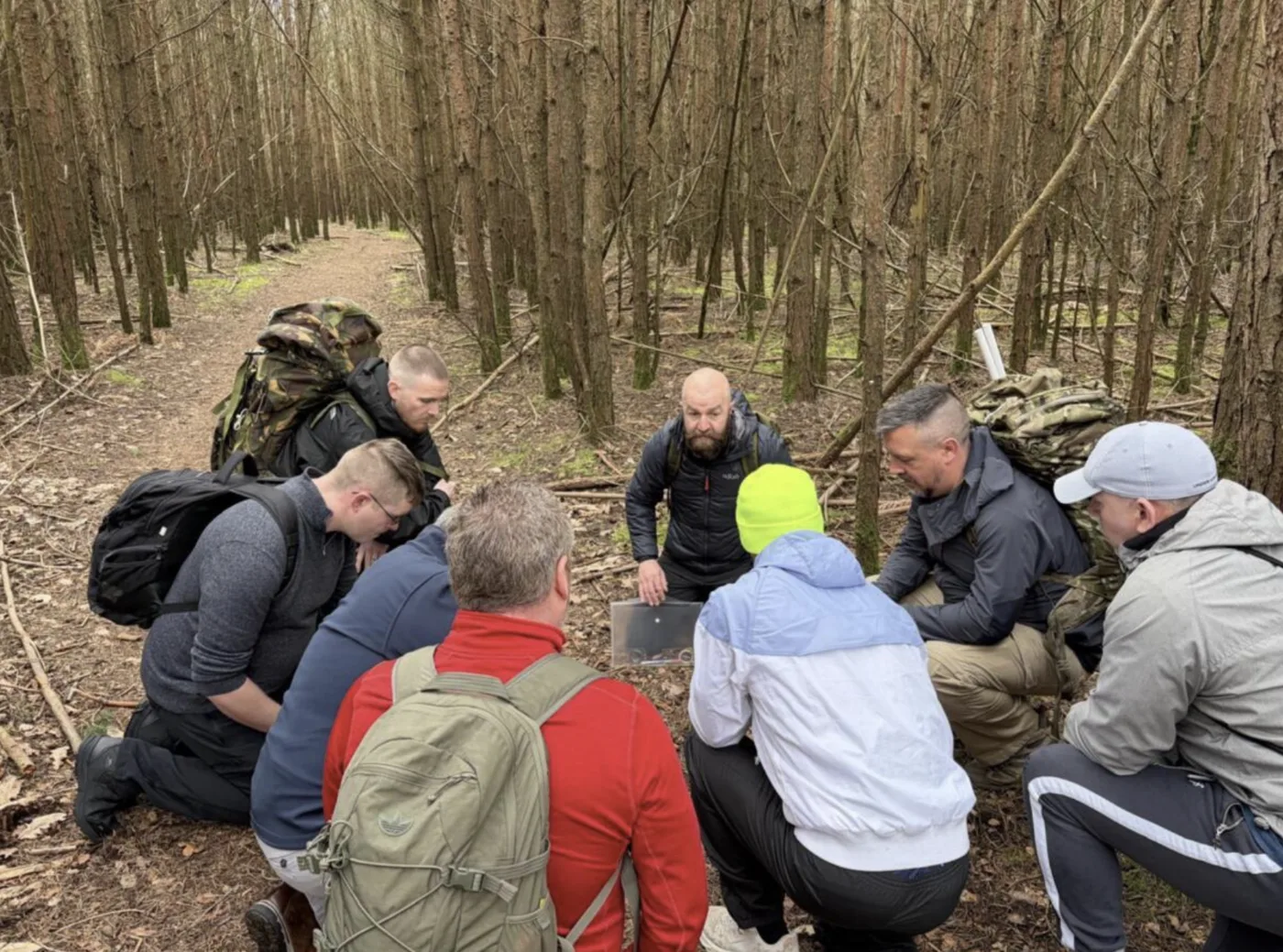 Leadership team huddle during outdoor field exercise in woodland