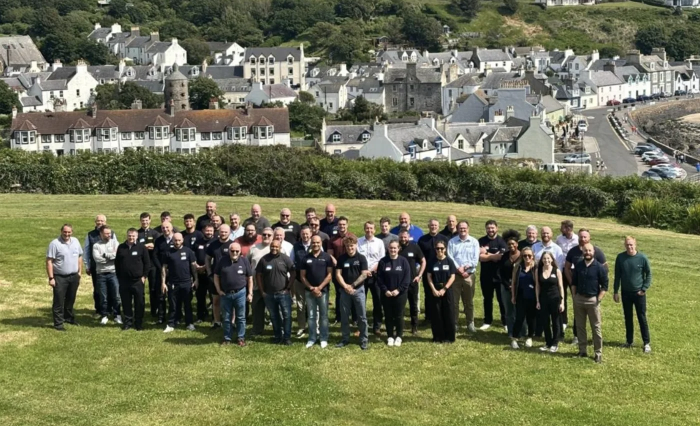 Programme delegates group photo on a hillside overlooking a coastal Scottish village